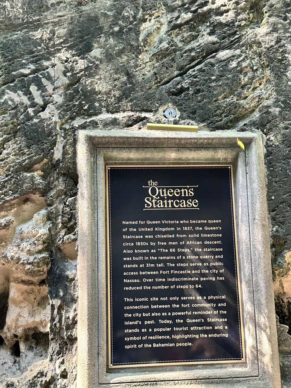 A dark bronze plaque headed The Queen's Staircase, set in a carved stone frame on the gorge wall, gives the history of the steps.