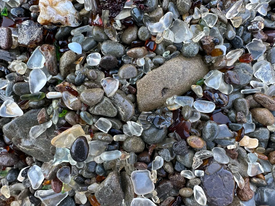 Gravel scattered with rounded pieces of white, brown and green glass.