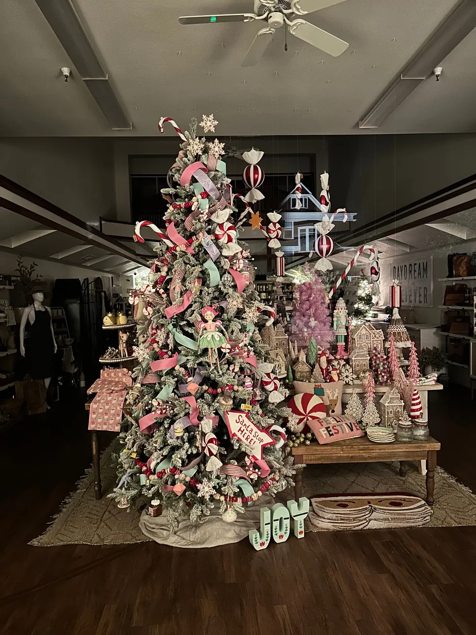 A tree covered in red-and-white candy decorations in a dark shop.