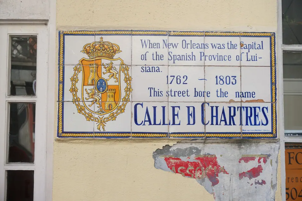 A blue-and-yellow tile plaque with a Spanish coat of arms reading Calle de Chartres, 1762-1803, on a plaster wall.