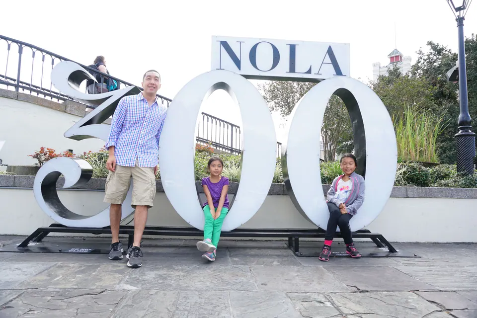 A man leans on the '3' while two girls sit inside the zeros of the giant 'NOLA 300' letters.