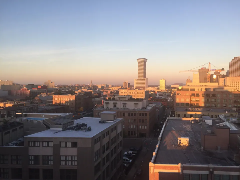 Early sun lights low brick rooftops and the downtown towers beyond under a pale sky.