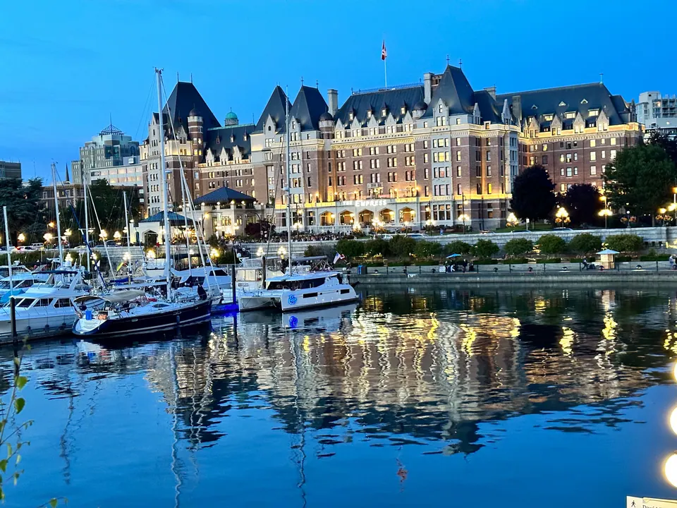 A large illuminated château-style hotel reflected in the still water of a marina at night.